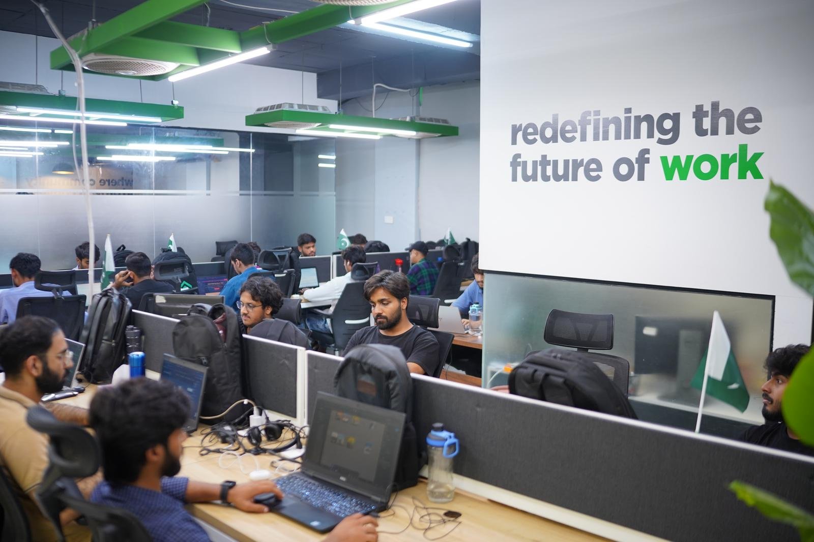 Busy open coworking floor at WorkX with a wall reading redefining the future of work